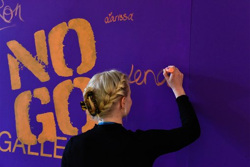 Eine junge Frau schreibt ihren Vornamen an eine Wand der Ausstellung.