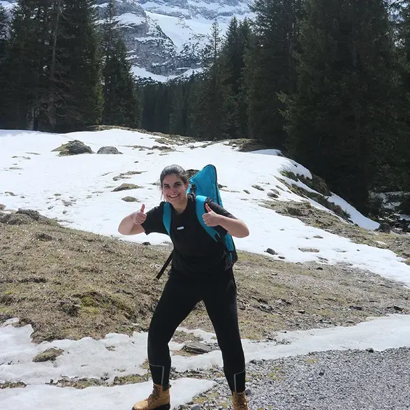 Stella Reichenbacher steht in einer verschneiten bergigen Landschaft und zeigt beide Daumen nach oben