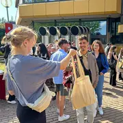 Vertreter:innen des AStA stehen auf dem Campus Kurt-Schumacher-Ring und verteilen die beliebten Ersti-Taschen.