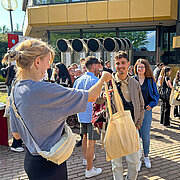 Vertreter:innen des AStA stehen auf dem Campus Kurt-Schumacher-Ring und verteilen die beliebten Ersti-Taschen.