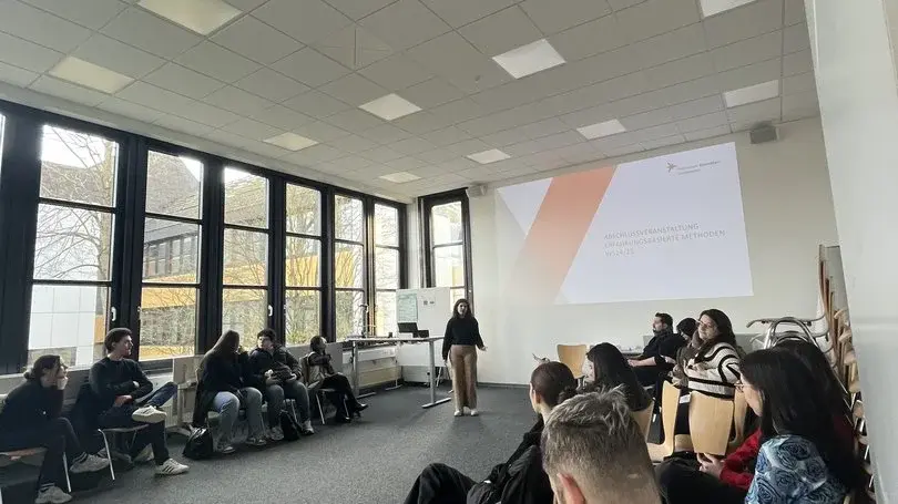 Gruppe sitzt sich in einem Raum gegenüber 