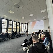Gruppe sitzt sich in einem Raum gegenüber 