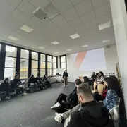 Gruppe sitzt sich in einem Raum gegenüber 