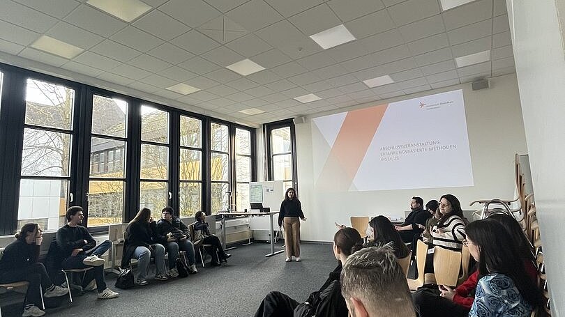 Gruppe sitzt sich in einem Raum gegenüber 