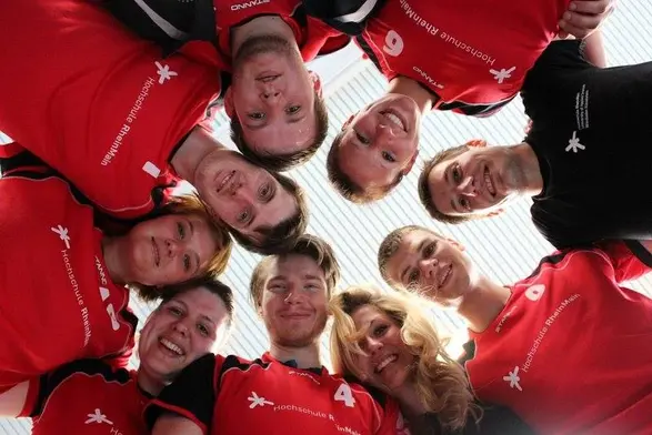 Spitzensportler:innen halten sich an den Schultern und stehen im Kreis