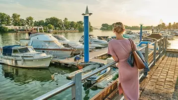 Eine blonde Frau schaut auf die Schiffe, die im Schiersteiner Hafen ankern