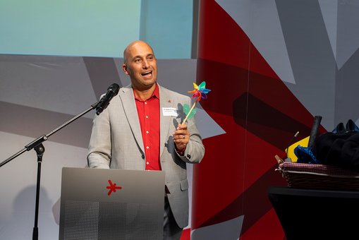 Hochschulkanzler Dr. Martin Lommel steht während seiner Abschiedsworte auf der Bühne und hält ein Windspiel in den Händen