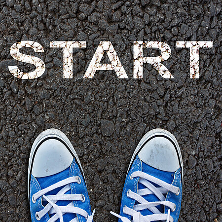 Zwei Schuhe auf der Straße vor dem Wort "START".
