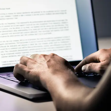 Hände, die an einem Laptop einen Text tippen.