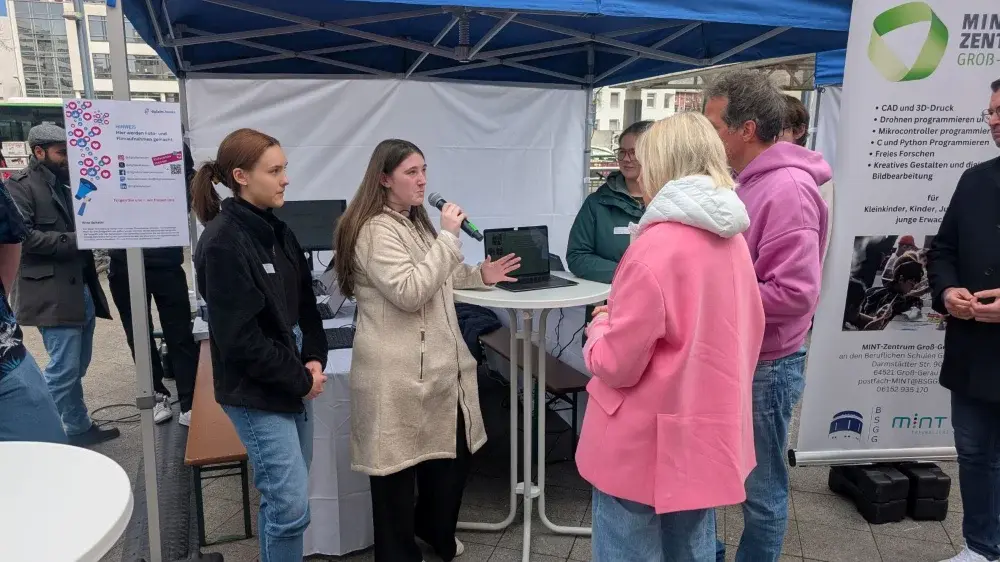 Schülerinnen erklären der Ministerin und Willi ihr KI-Projekt der Nachhaltigkeit 