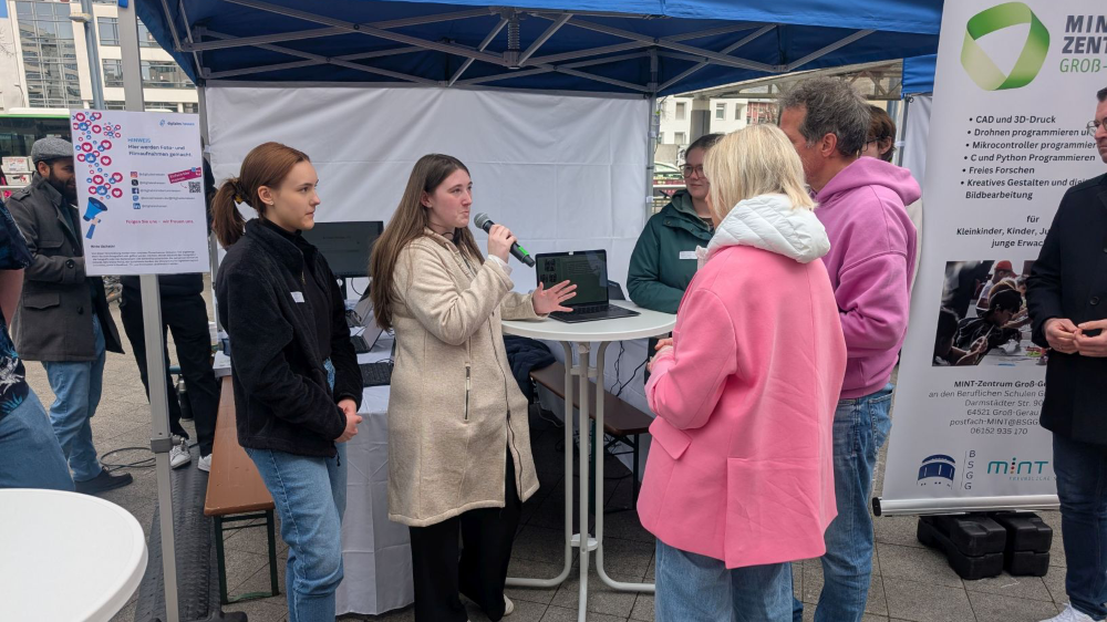 Schülerinnen erklären der Ministerin und Willi ihr KI-Projekt der Nachhaltigkeit 