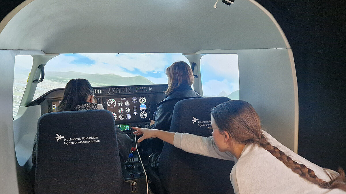 Drei Teilnehmerinnen sitzen im Cockpit des Flugsimulators   