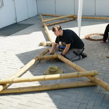 A student builds a roof structure out of bamboo.