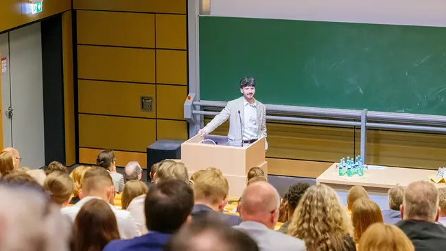 Moritz Mühlhausen steht am Rednerpult im Großen Hörsaal am Campus Rüsselsheim
