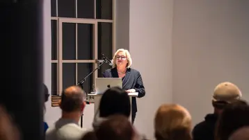 Prof. Dr. Eva Waller steht hinter einem Pult vor Publikum und hält ein Grußwort anlässlich des BDA Studienpreises 2025.