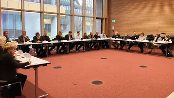 A group of people, the external advisory board of the RITMO research group, are seated at a large rectangular table in a conference room in Building G on the Kurt-Schumacher-Ring campus.
