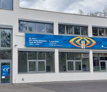 Blick auf einen großen Screen an einer Gebäudefassade, darauf Werbung für die Jubiläumsveranstaltung 60 Jahre ZDF Unter den Eichen