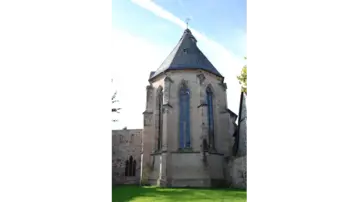 Exterior view of the apse of Alsfeld Monastery. Historic church building with a high, pointed roof and striking, tall windows.