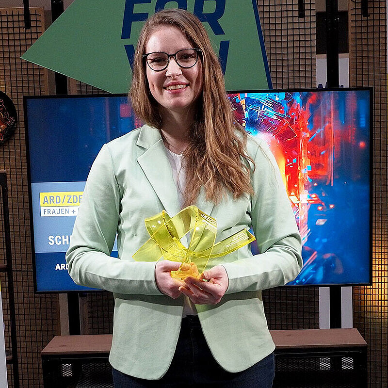Maike Kaiser hält die Siegerinnen-Trophäe des ARD/ZDF Förderpreises „Frauen + Medientechnologie“ in den Händen.