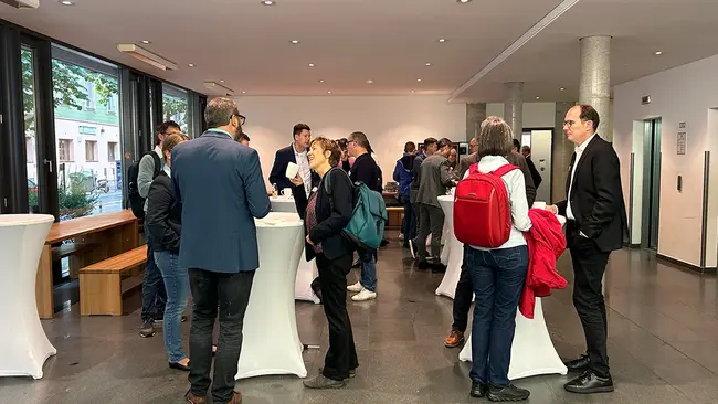 Eine Gruppe von Menschen steht an mehreren Stehtischen