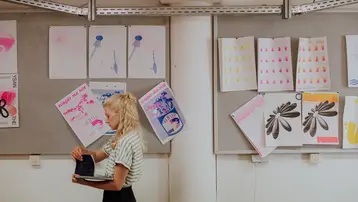 Studierende vor Druckprodukten in der Druckwerkstatt des Studiengangs Kommunikationsdesign