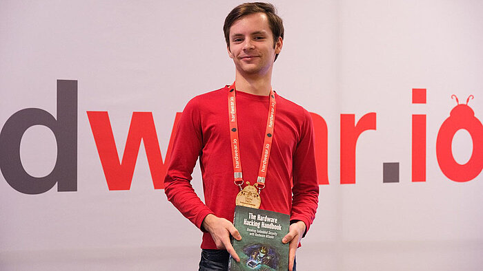 Der Zweitplatzierte Daniel Hahn hält ein Buch über Hacking in der Hand