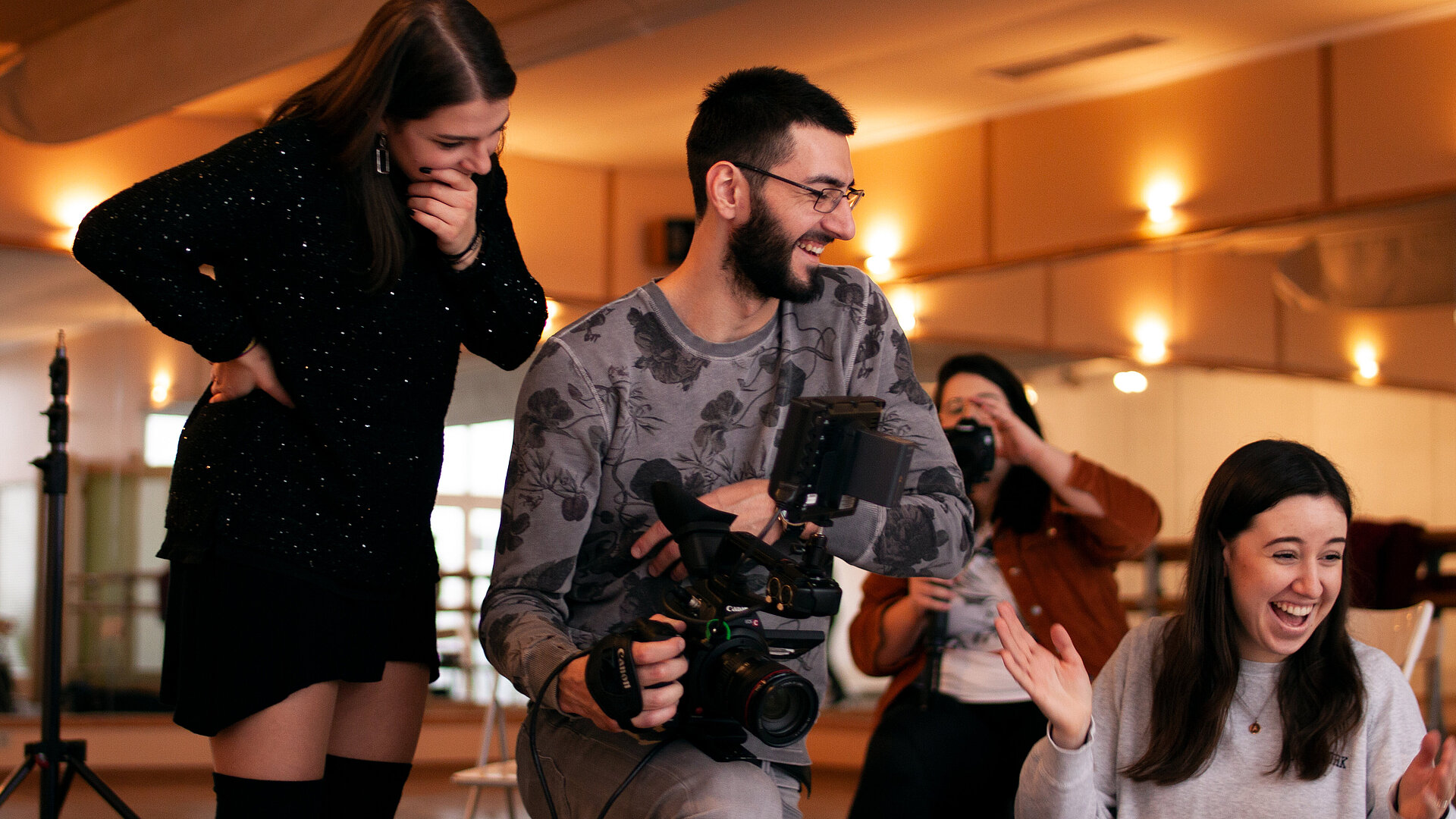 MCP Studierende zwei Studentinnen und ein Student, der eine Filmkamera hält, lachen