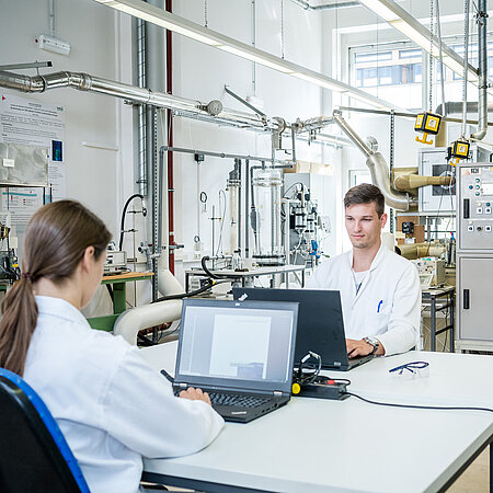 Bildaufnahme vom Verfahrenstechniklabor mit drei forschenden Personen 