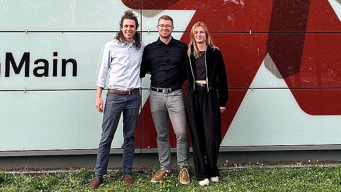 Das Gründungsteam der namowo GmbH steht vor einem Gebäude der Hochschule RheinMain.