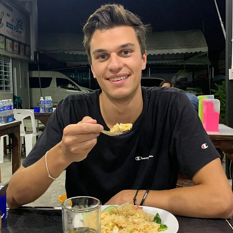 Justus Hamberger sitzt an einem Tisch und führt einen Löffel mit Essen zu seinem Mund