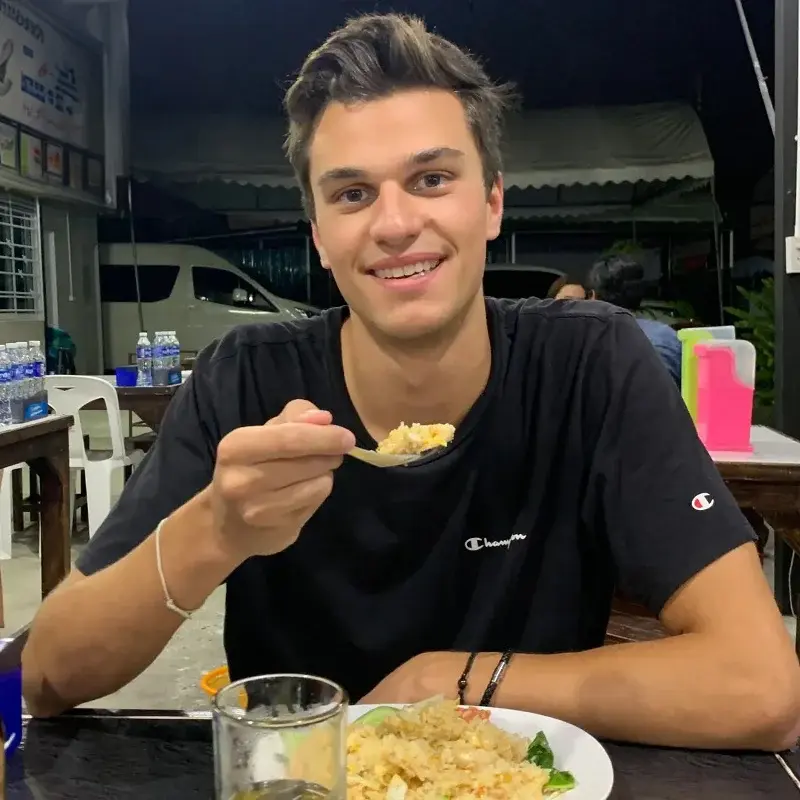 Justus Hamberger sitzt an einem Tisch und führt einen Löffel mit Essen zu seinem Mund