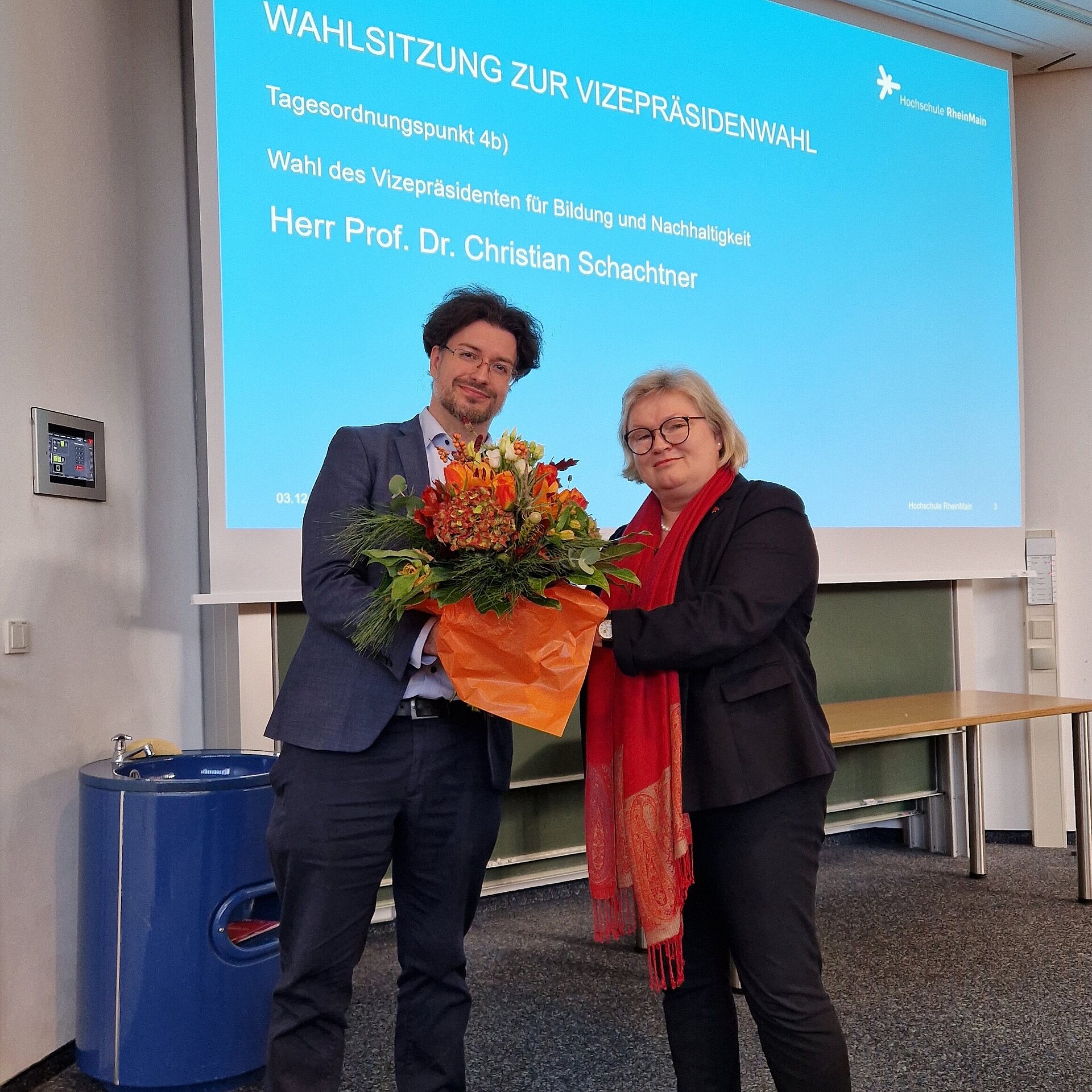 Prof. Dr. Eva Waller überreicht Prof. Dr. Christian Schachtner einen Blumenstrauß