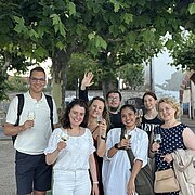 Die Teilnehmenden im Rheingau lächeln mit einem Glas Wein in die Kamera. 