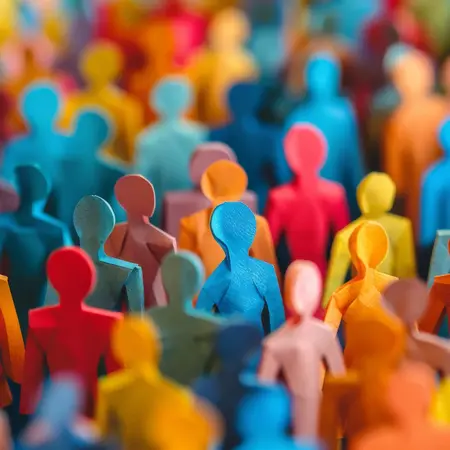 Ein dicht gedrängtes Feld aus bunten, stilisierten menschlichen Figuren in verschiedenen Farben. Die Figuren sind in zwei Dimensionen dargestellt und stehen in einem Muster, das Vielfalt symbolisiert. Die Szenerie vermittelt ein Gefühl von Gemeinschaft und Zusammenhalt.