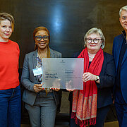 Kathrin Peltz, Prof. Dr. Abiola Sarnecki, Prof. Dr. Eva Waller und Dr. Volker Meyer-Guckel halten eine Plakette in die Kamera