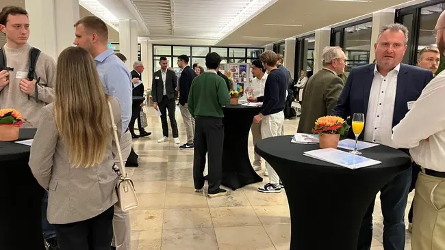 Am Campus Rüsselsheim stoßen die Anwesenden an Stehtischen mit Sekt auf die Verleihung der Deutschlandstipendien an
