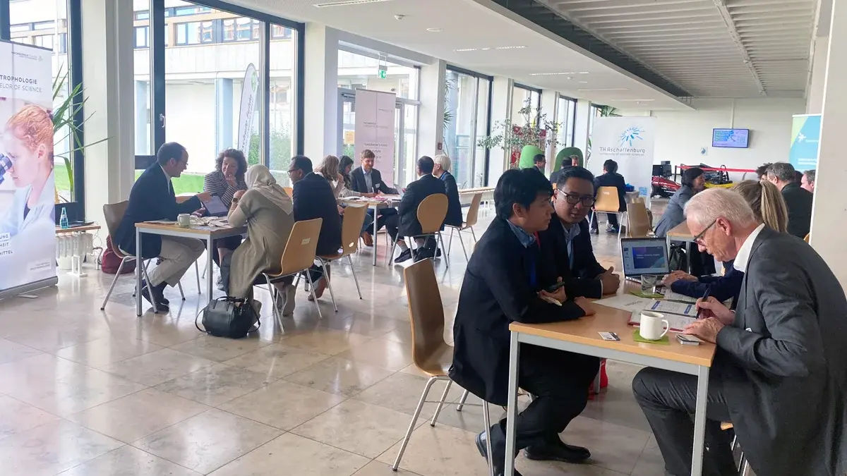 Im Foyer am Campus Rüsselsheim sitzen viele Menschen an Tischen