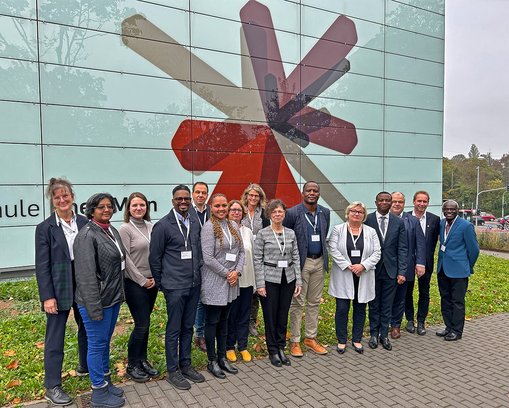 Vertreter:innen der Namibia University of Science and Technology und der Hochschule RheinMain stehen für ein Gruppenfoto vor dem G-Gebäude der Hochschule RheinMain auf dem Campus Kurt-Schumacher-Ring in Wiesbaden