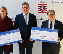 Staatssekretär Stefan Sauer (m.) mit Prof. Dr. Melanie Siegel (h_da) und Prof. Dr. Marc Stöttinger (HSRM). 