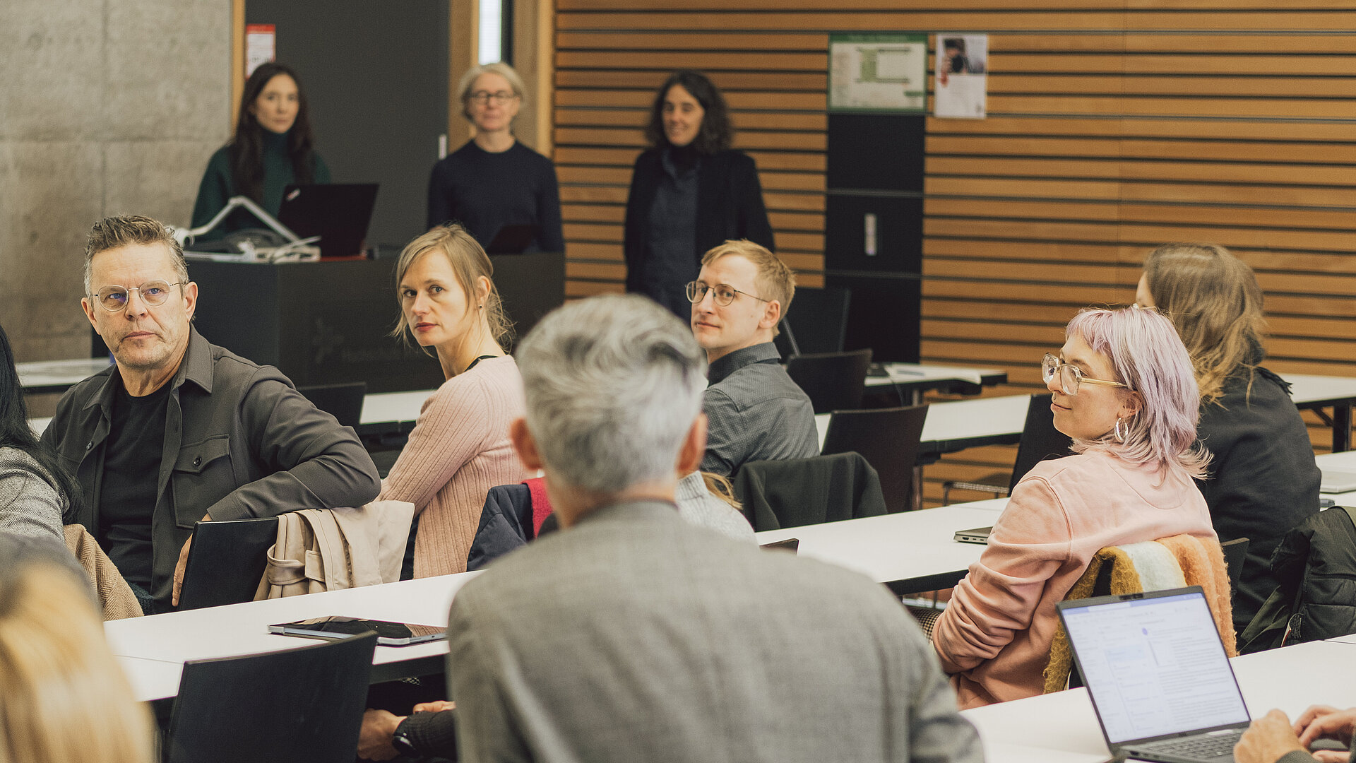 Plenum guckt sprechende Person an Person spricht, Rest schaut die sprechende Person an