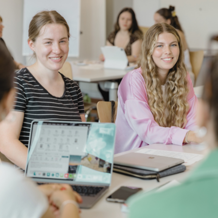 Zwei Studierende sitzen nebeneinander und lächeln 