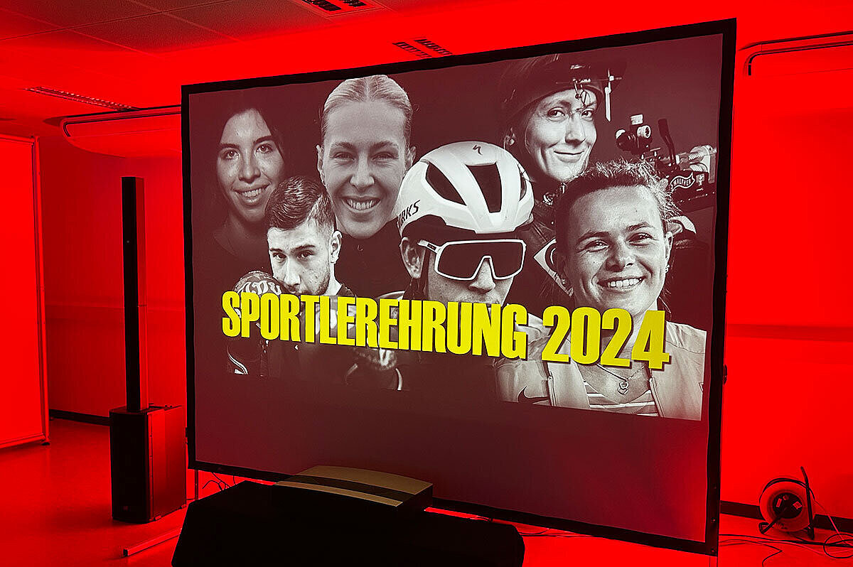 Blick auf die Leinwand mit einer Collage von Spitzensportler:innen der Hessischen Hochschule für öffentliches Management und Sicherheit und der Hochschule RheinMain, darüber der Text „Sportlerempfang 2024“
