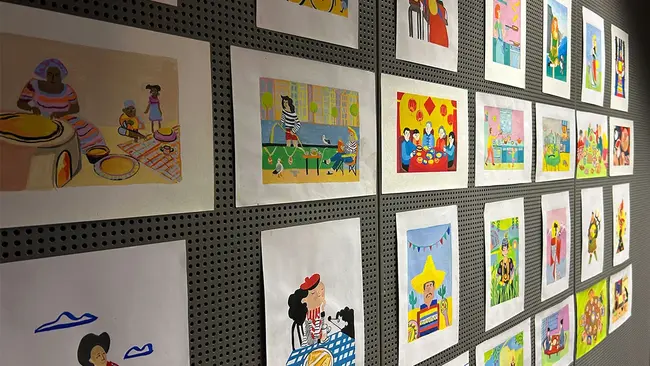 An einer Wand hängen Motive des des Kochbuchs „Pfannkuchen“ von Tamara Bezgina.