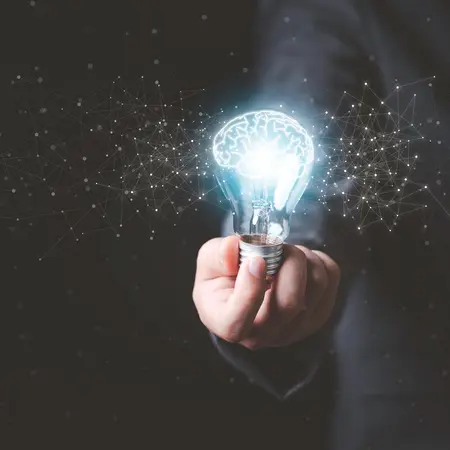 Geschäftsmann, der eine leuchtende Glühbirne mit einer Zeichnung eines Gehirns und einer Verbindungslinie hält; Ideen für kreatives Denken und Innovationskonzepte.