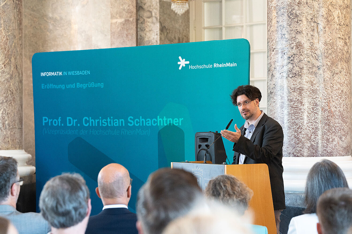 Prof. Dr. Christian Schachtner steht während seines Grußworts am Rednerpult und spricht ins Mikrofon.
