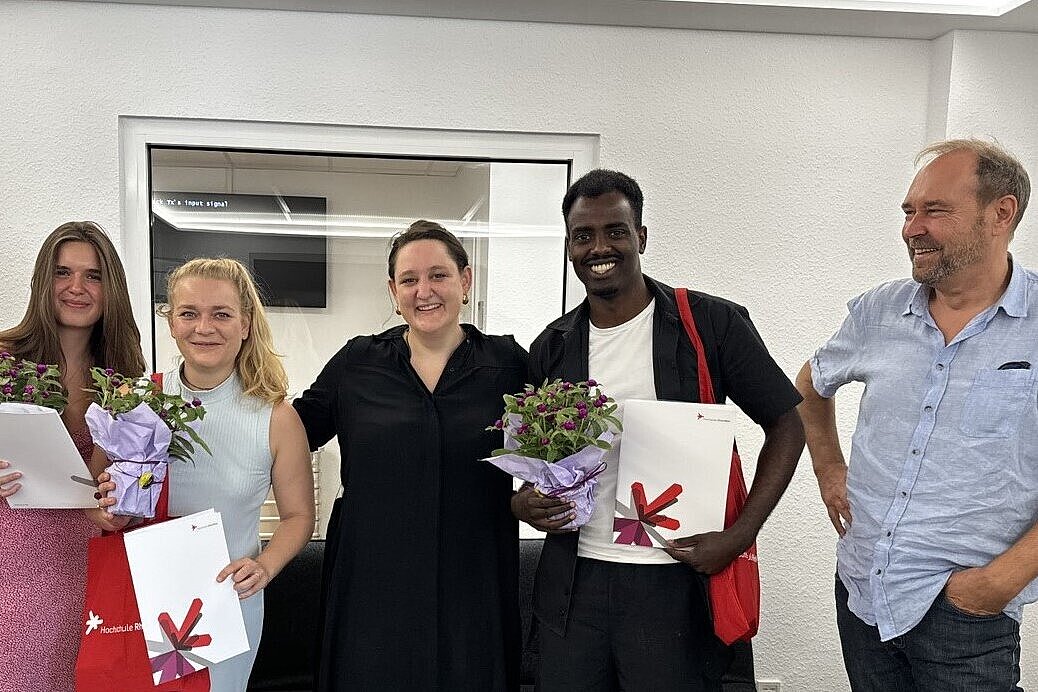 Personen stehen nebeneinander und lächeln in die Kamera. Sie halten Blumen und Zertifikate in ihren Händen 