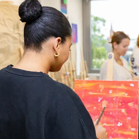 Studentin malt ein Bild an der Staffelei