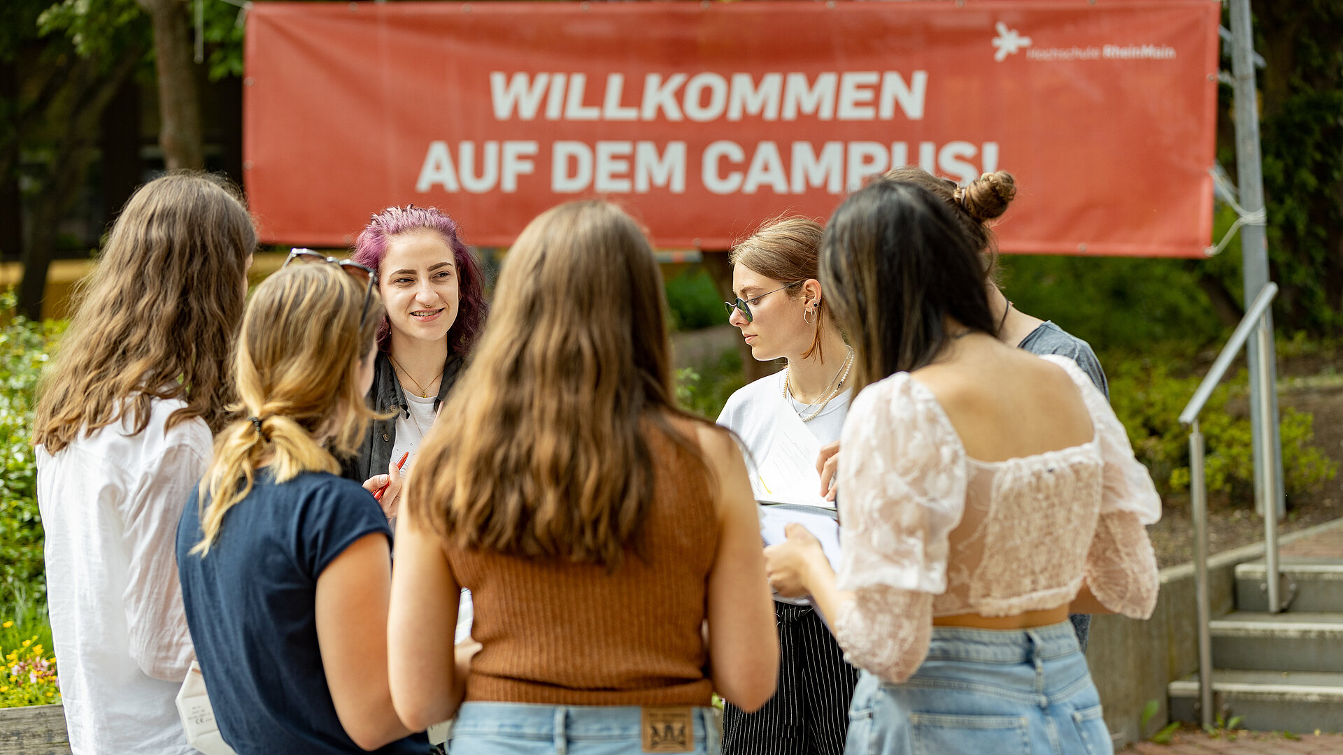 Eine Gruppe junger Menschen unterhält sich im Freien auf dem Campus