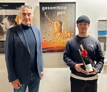 Prof. Rüdiger Pichler und Kommunikationsdesign-Student Tim Weishaupt stehen vor dessen Plakat