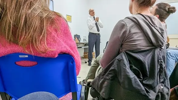 zwei Frauen sitzen auf Stühlen und werden von hinten fotografiert